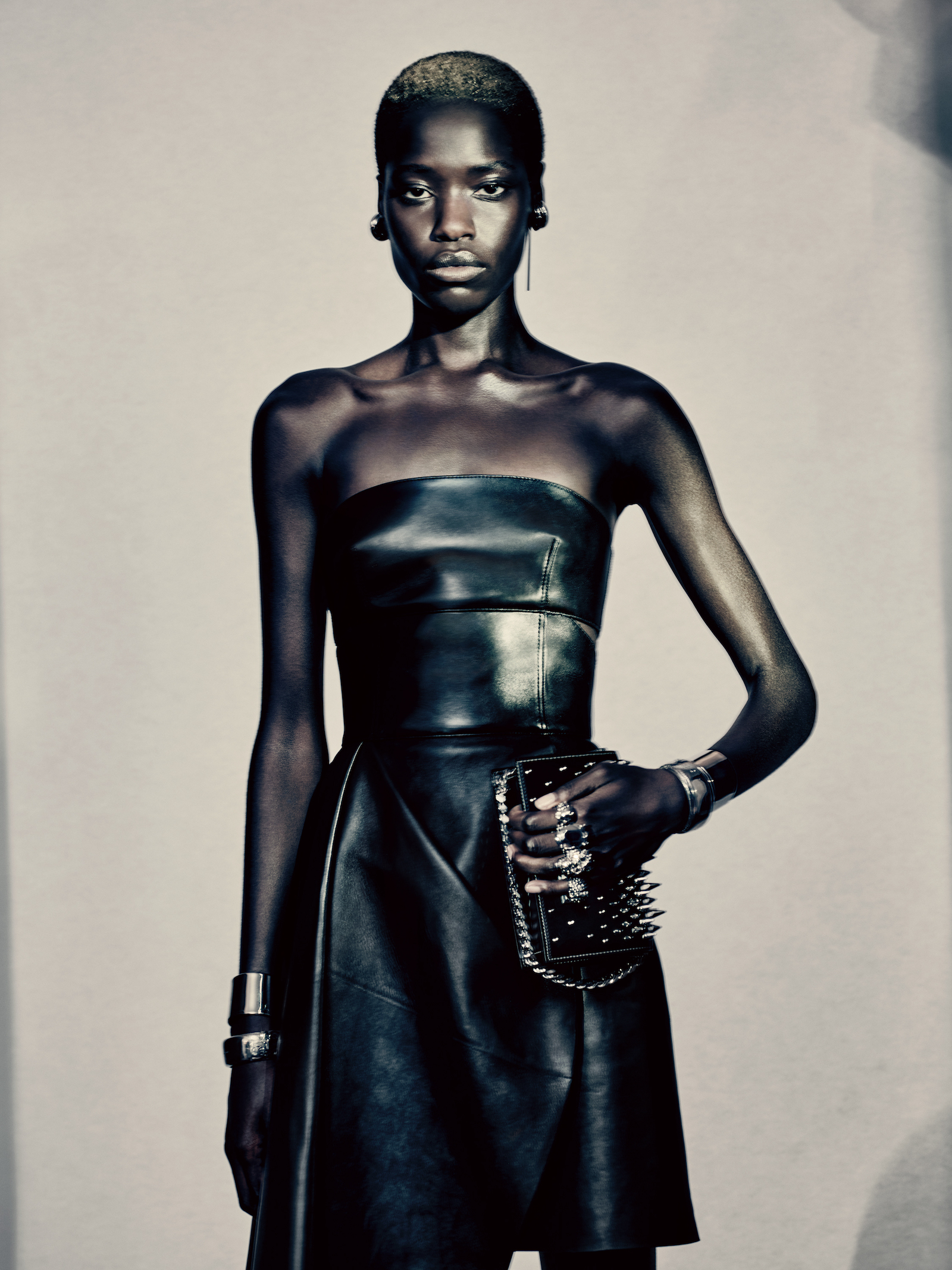  Awar wears the black slashed bustier dress with a draped skirt, black jeweled satchel bag, and antique silver studs, photographed by Paolo Roversi.